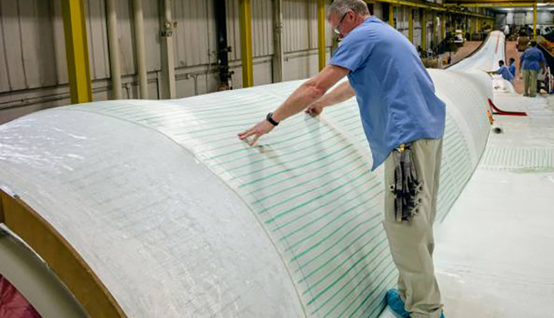  עובד מתאים בד פיברגלס על תבנית להבים במפעל להבי הטורבינות של סימנס AG בפורט מדיסון, איווה, ארה